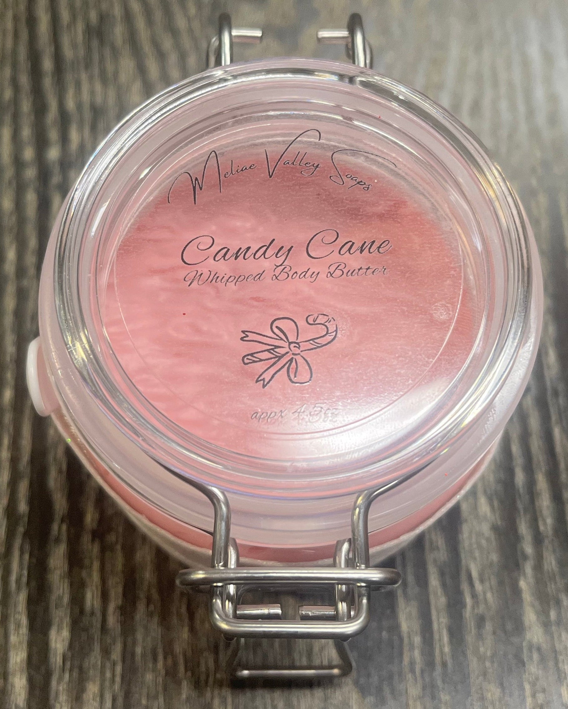 Clear round jar with a sticker on top. You see through to the jar to pink body butter. 