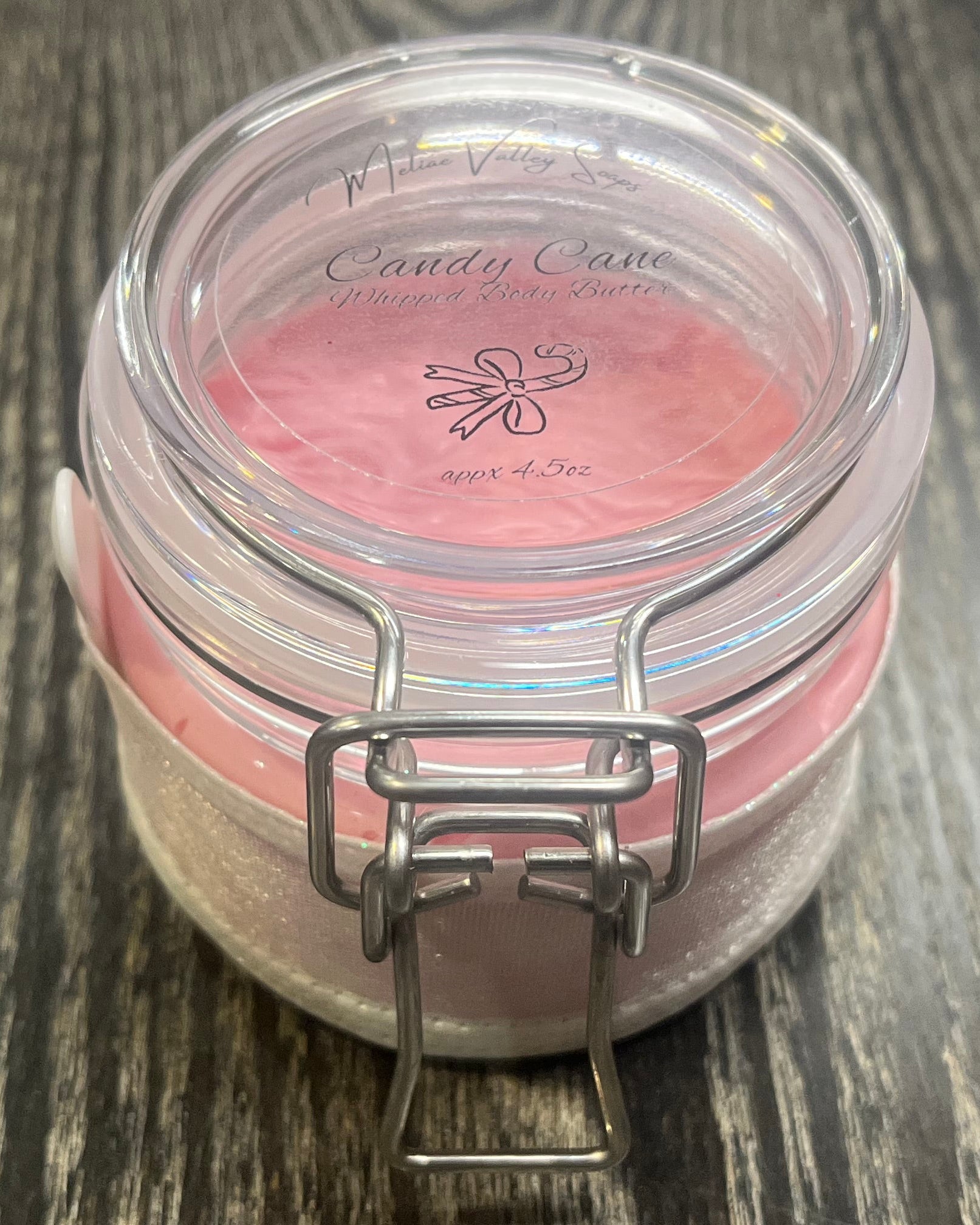 Clear round jar with a sticker on top. You see through to the jar to pink body butter. 