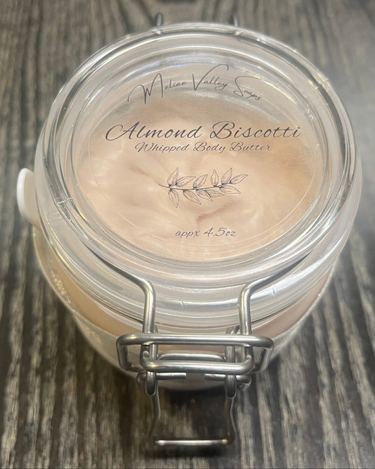 Clear round jar with a sticker on top. You see through to the jar of bronze body butter. 