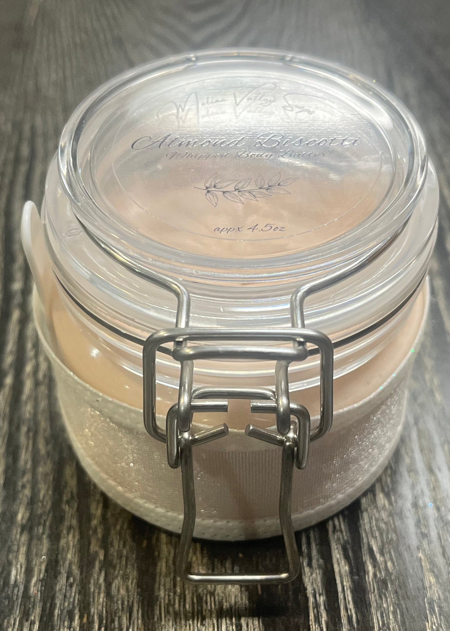 Clear round jar with a sticker on top. You see through to the jar to bronze body butter. 