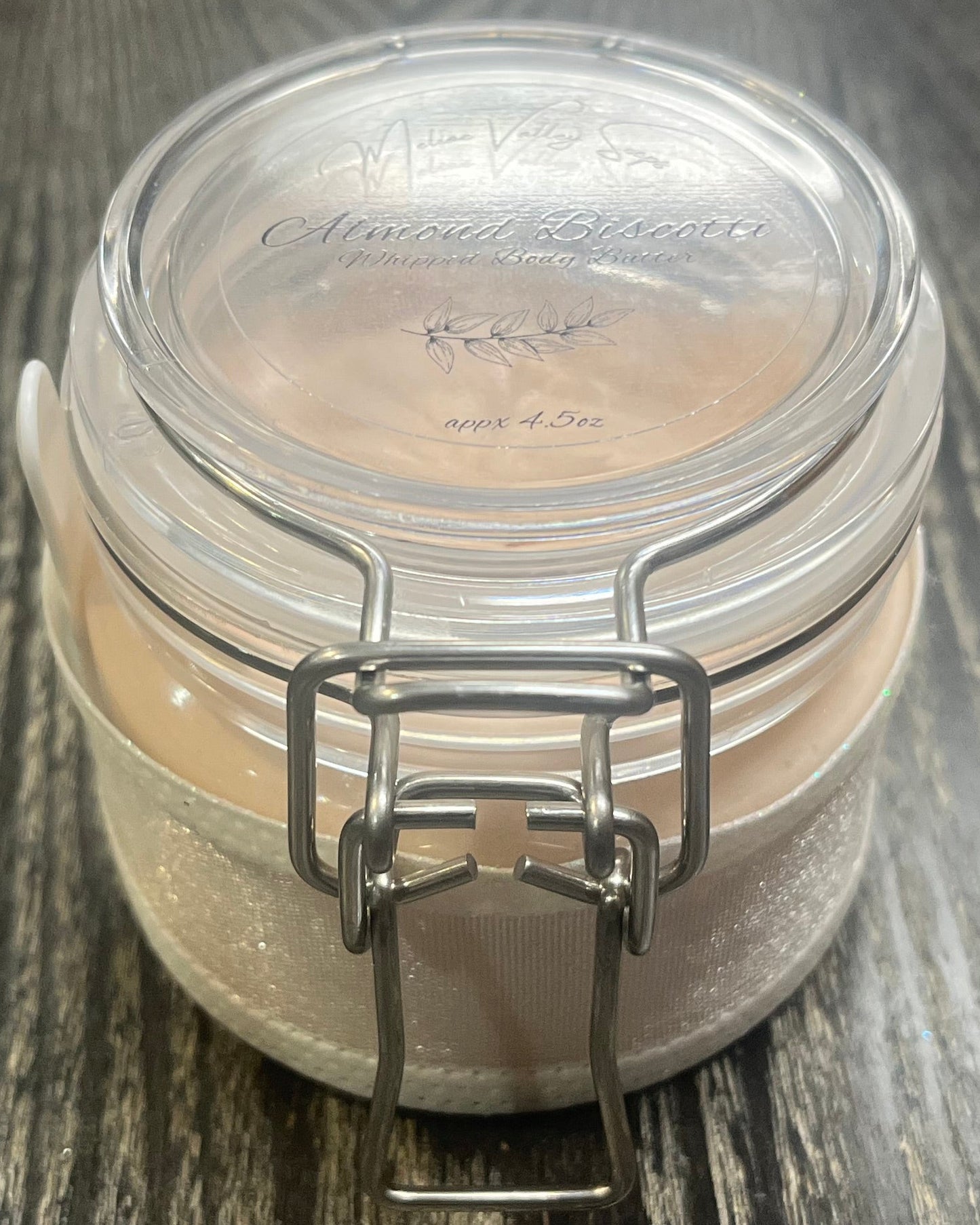Clear round jar with a sticker on top. You see through to the jar to bronze body butter. 