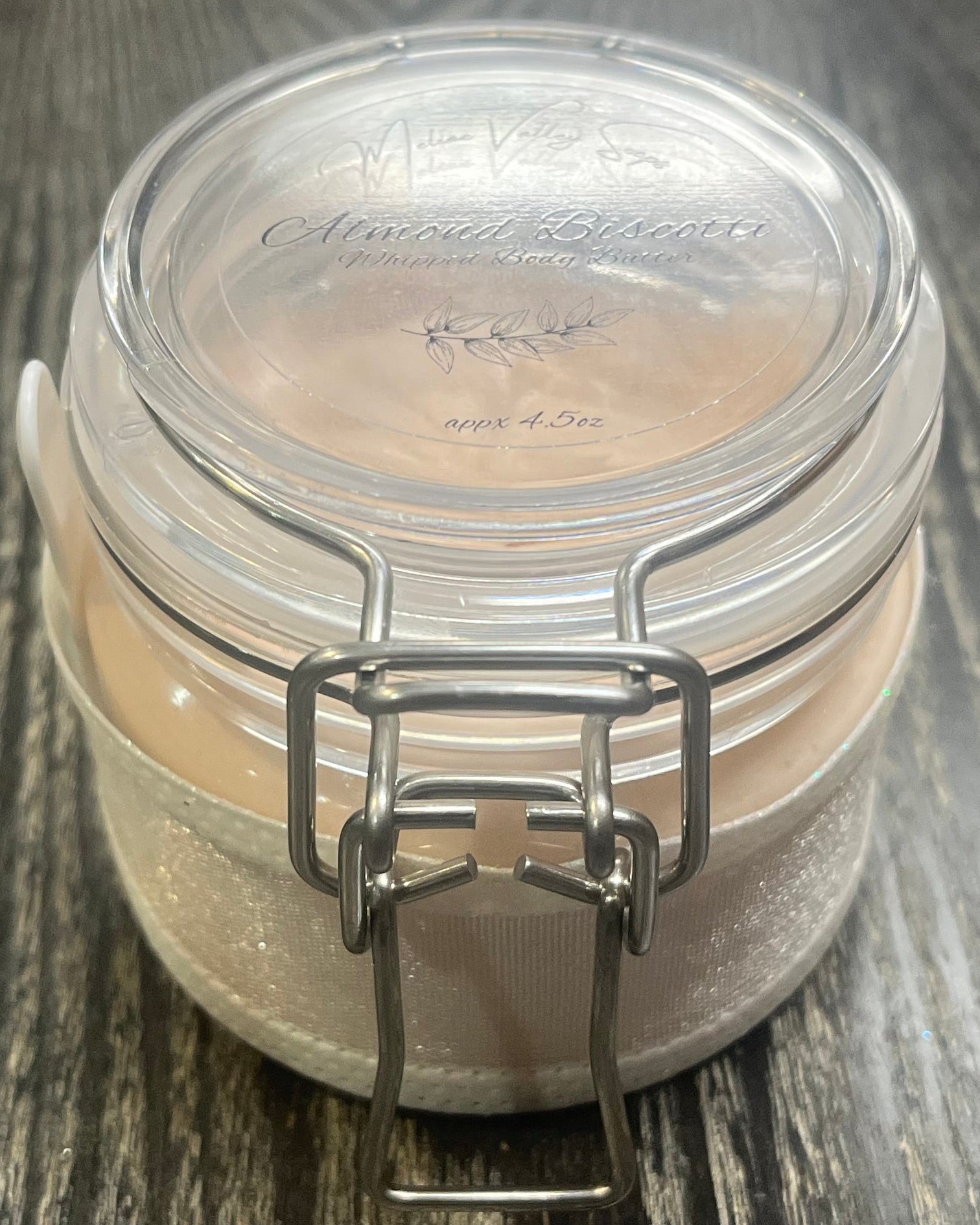 Clear round jar with a sticker on top. You see through to the jar to bronze body butter. 