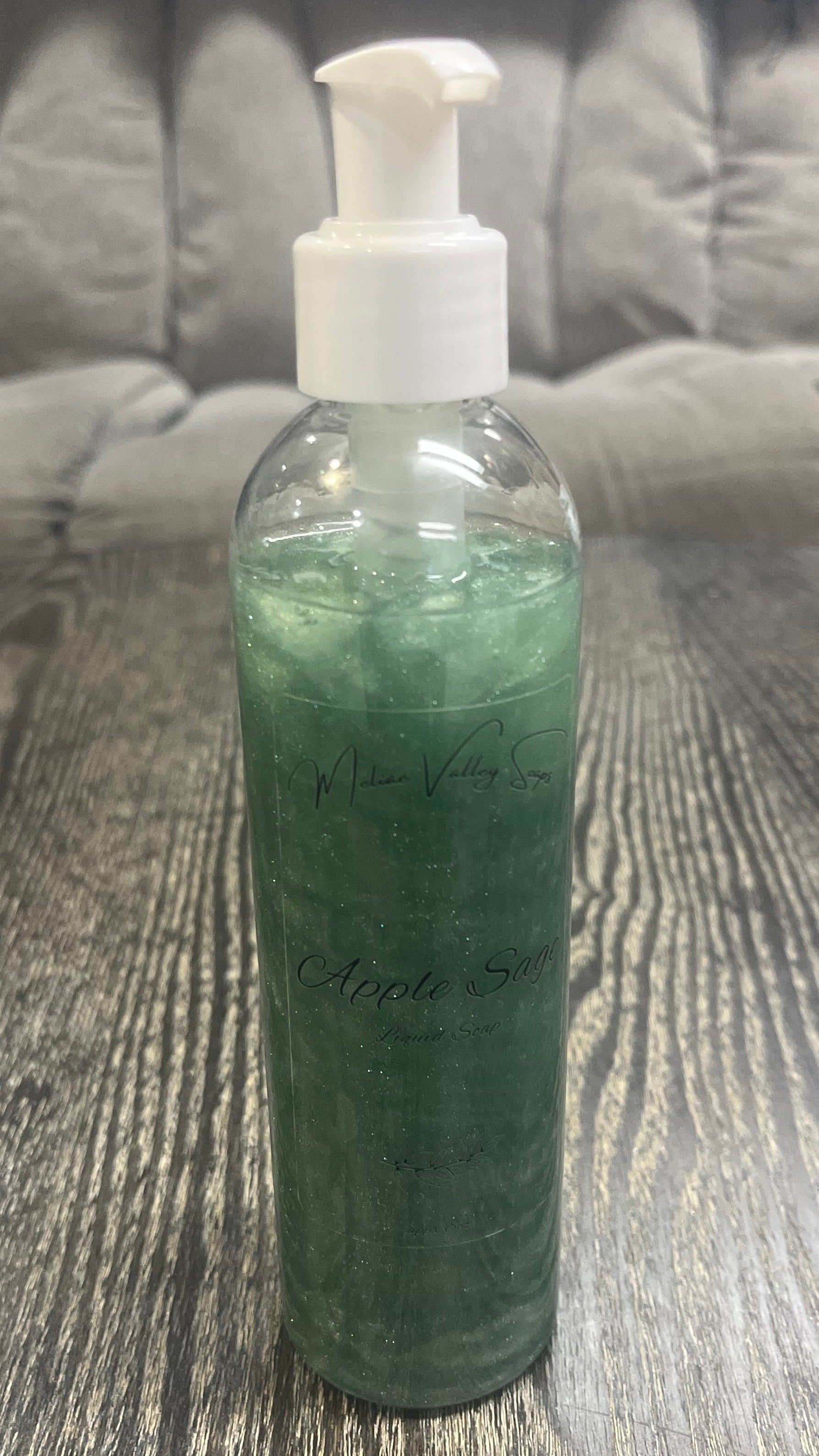 A clear pump bottle with a white nozzle full of green liquid on a textured surface. 