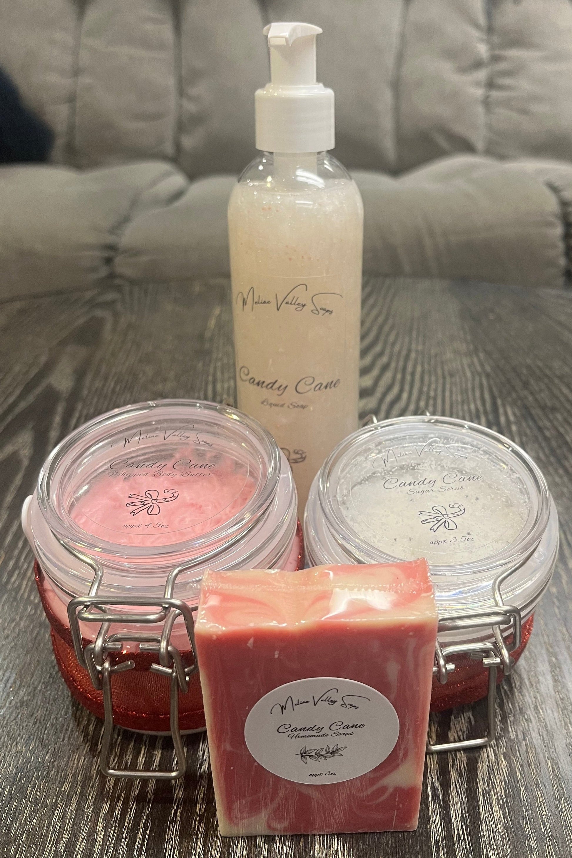 A set of beauty products, including a bottle, jars, and a bar on a textured surface.