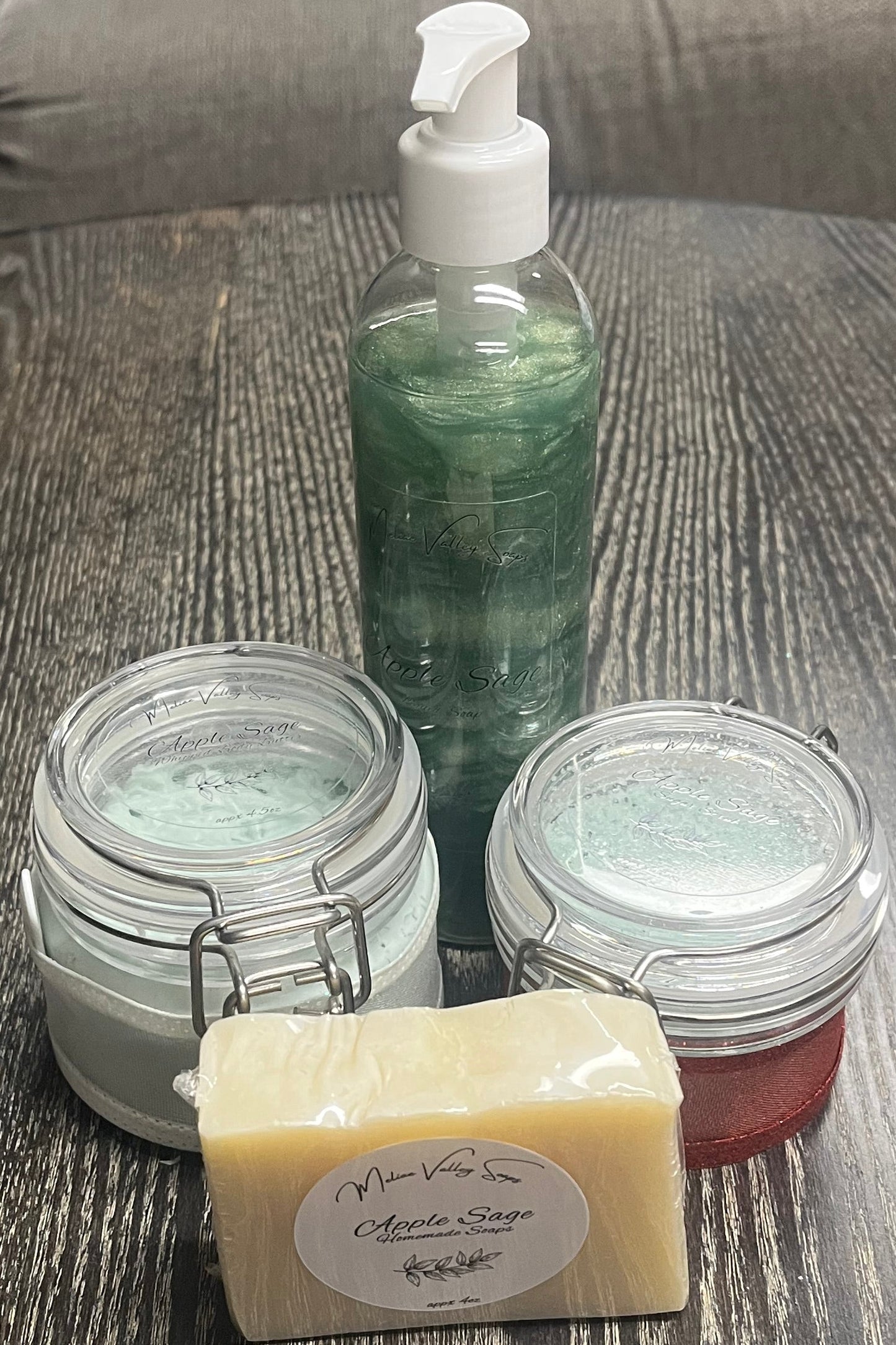 A set of beauty products, including a bottle, jars, and a bar on a textured surface.