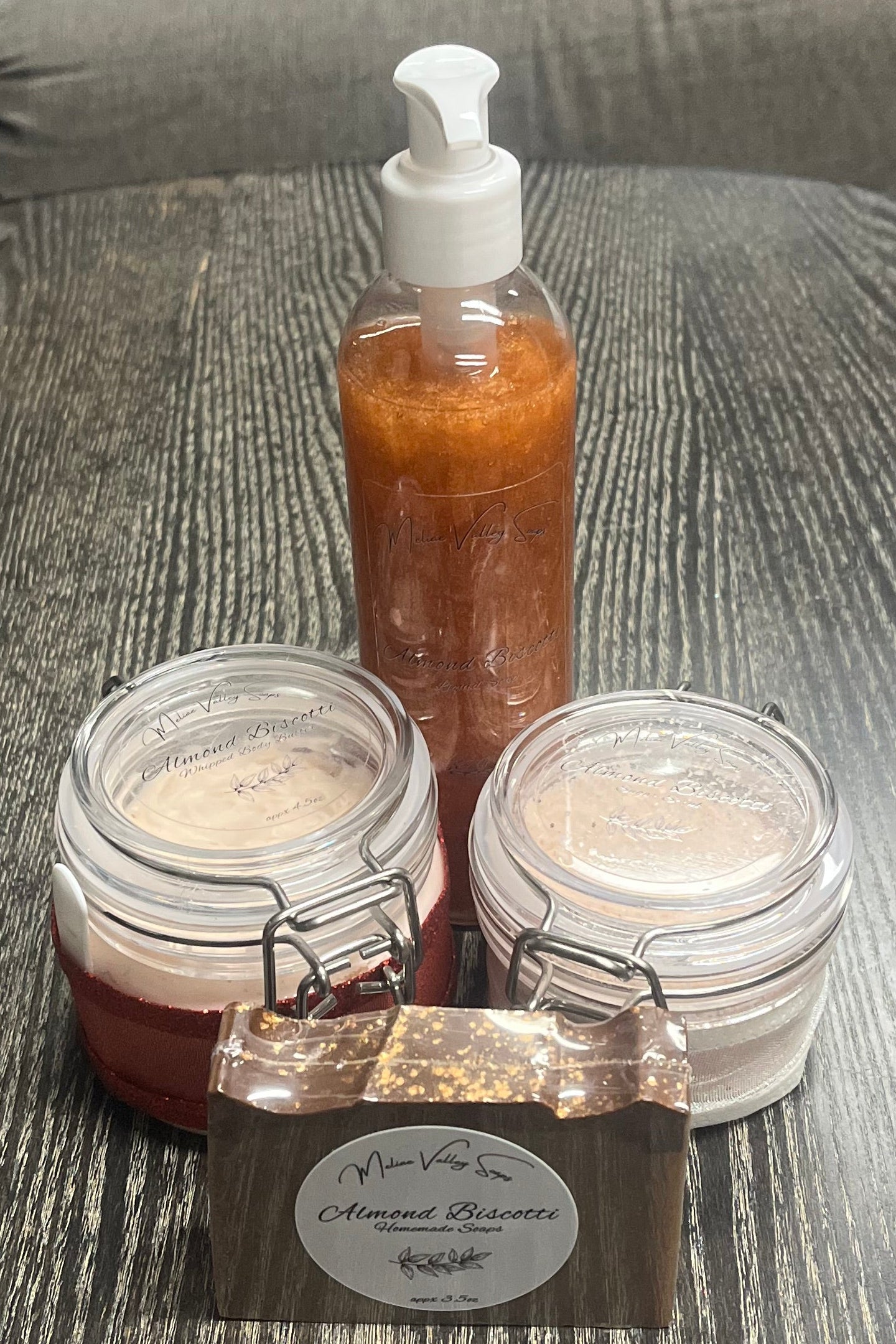 A set of beauty products, including a bottle, jars, and a bar on a textured surface.