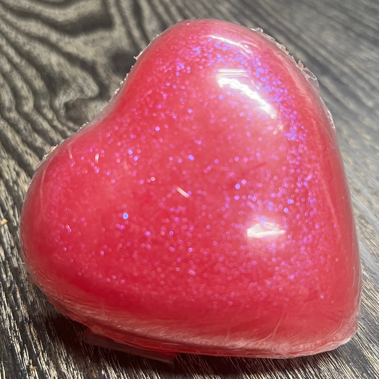 Pink glittery heart-shaped soap bar on a wooden surface.