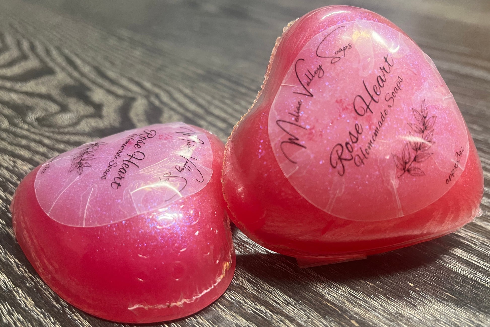 Two pink heart-shaped soap bars with a clear label.