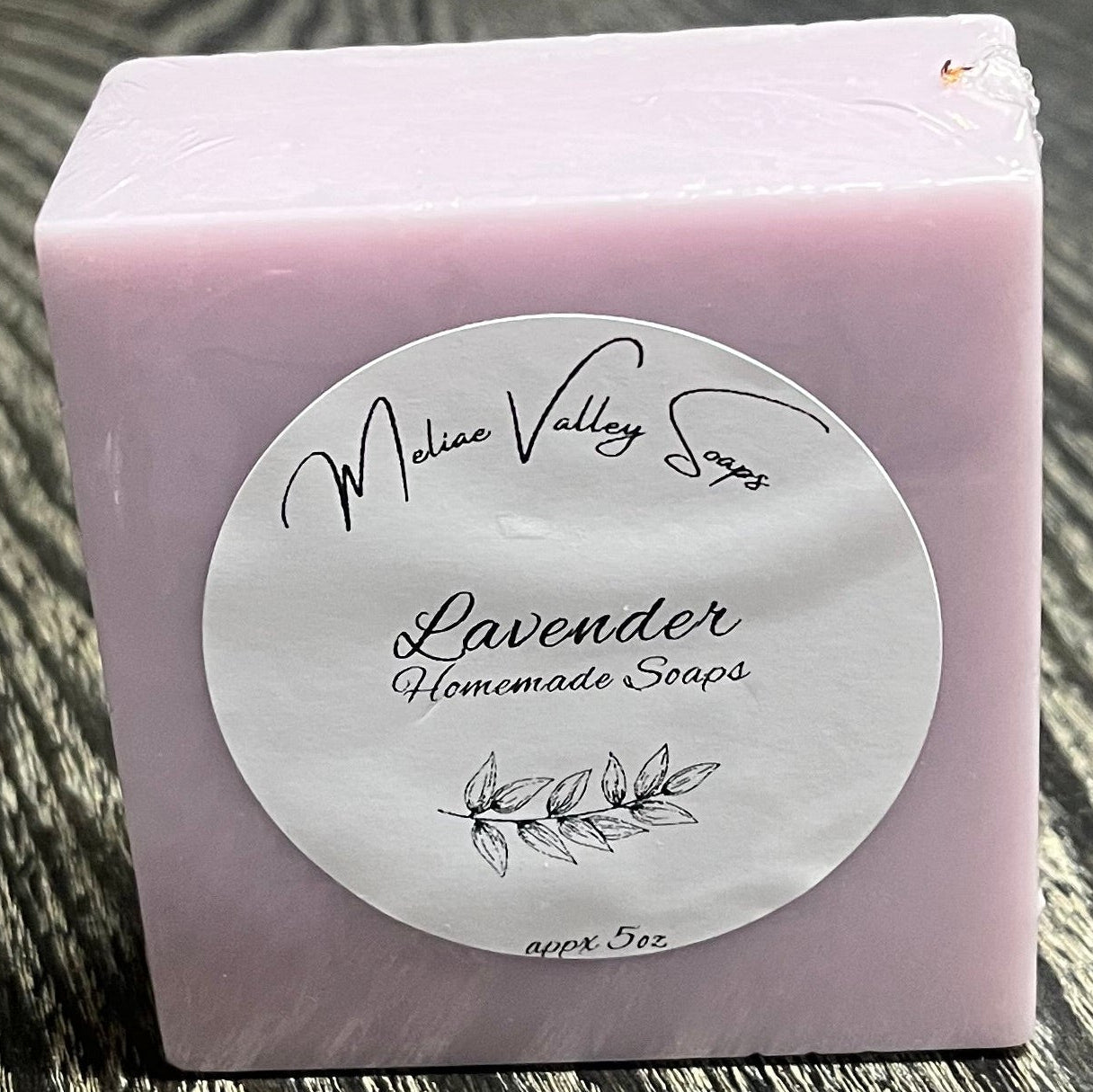 A bar of purple soap with a white label on a textured surface. 