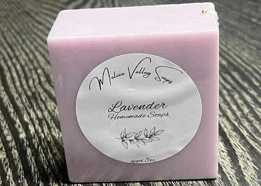 A bar of purple soap with a white label on a textured surface. 