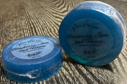 Two blue soap bars with clear labels. One is lying face down, the other is upright. 