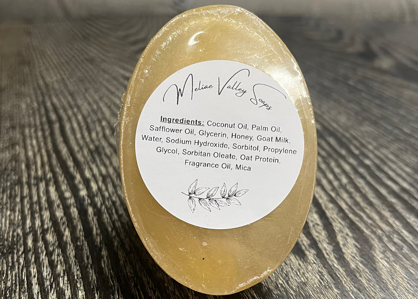 A bar of amber soap with a white ingredients label. It is upright to show the bottom of the bars. 
