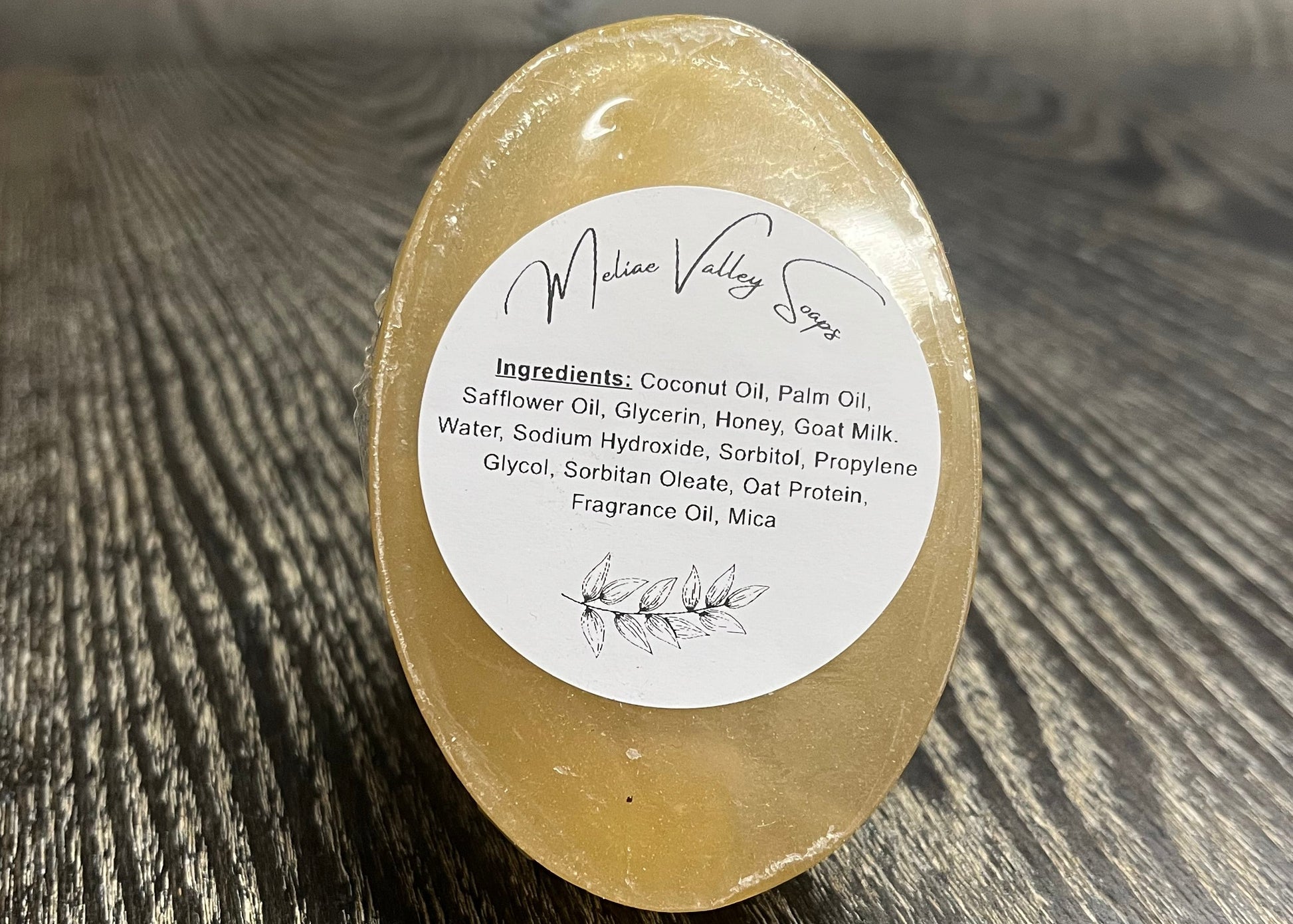 A bar of amber soap with a white ingredients label. It is upright to show the bottom of the bars. 