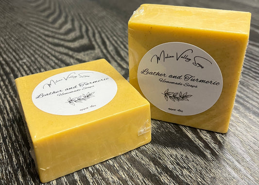 Two yellow soap bars with labels on a wooden surface.