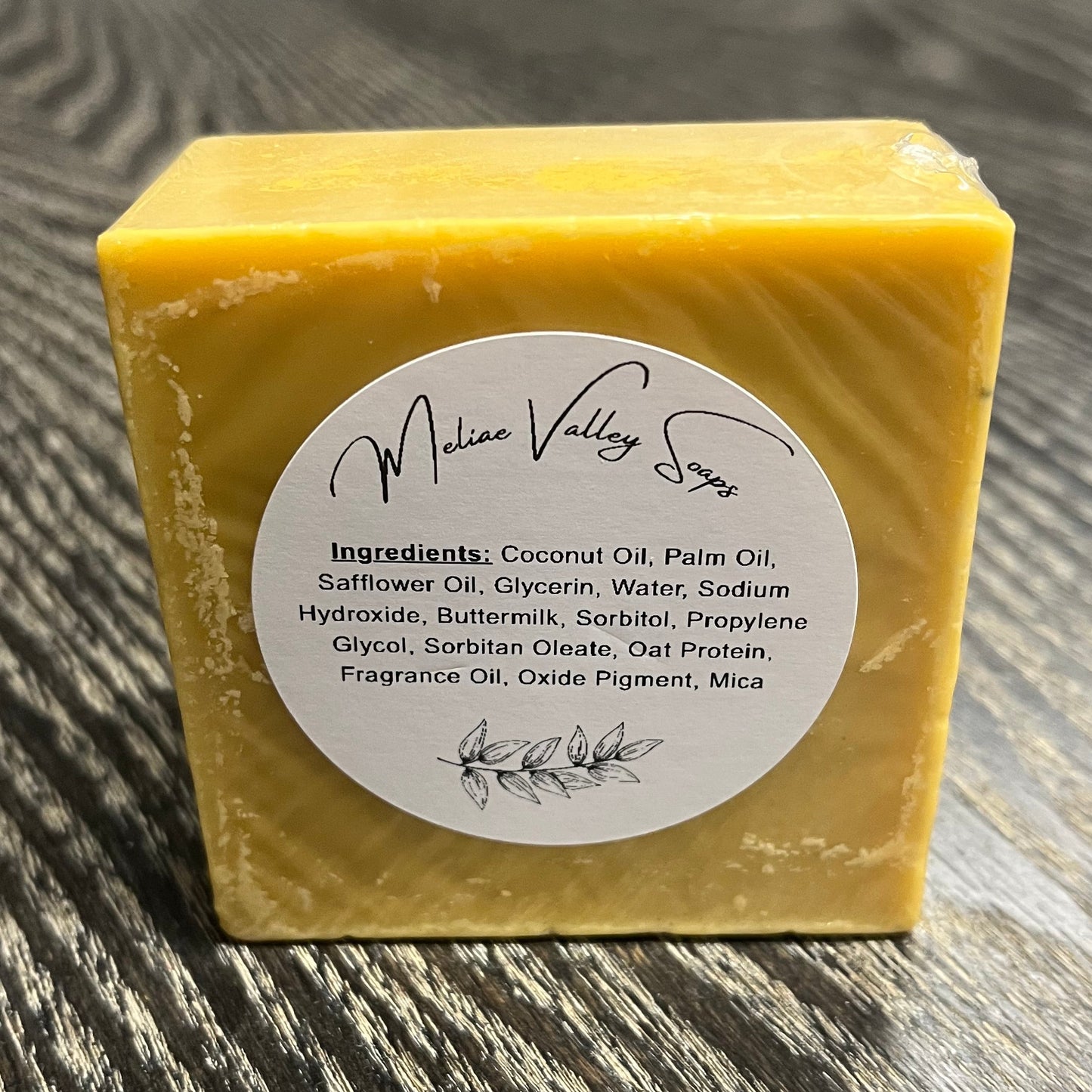 Yellow soap bar with a label on a wooden surface.