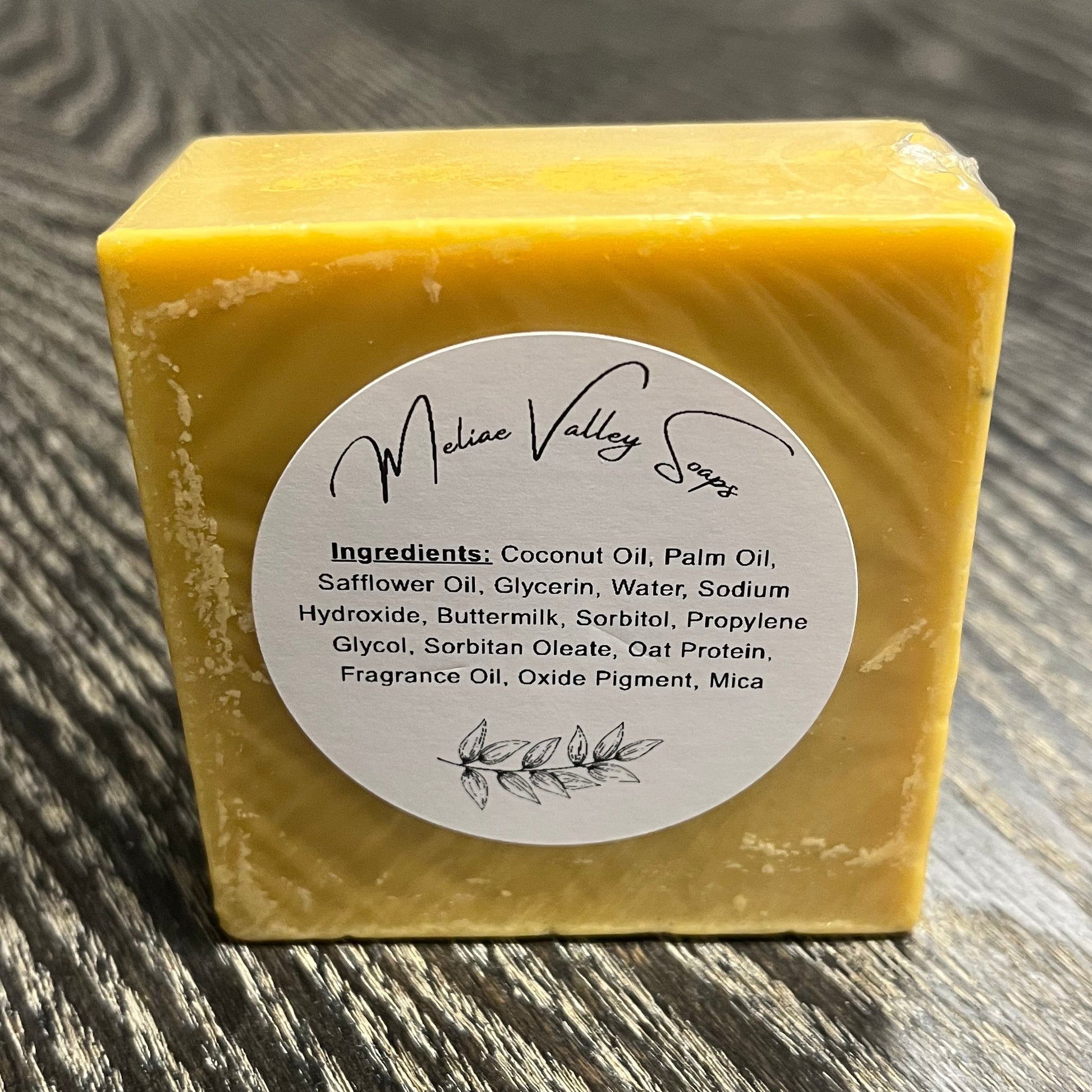 Yellow soap bar with a label on a wooden surface.