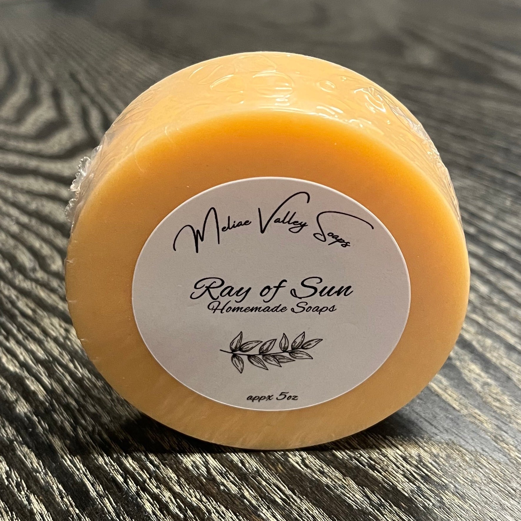 Round orange bar of soap with a label on a wooden surface.