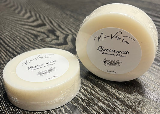 Two round soap bars with labels on a wooden surface. 