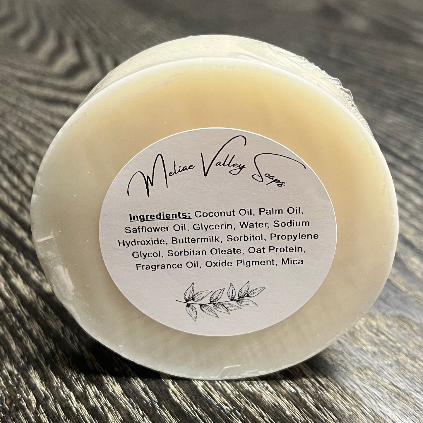 Bar of soap with a label on a wooden surface. 