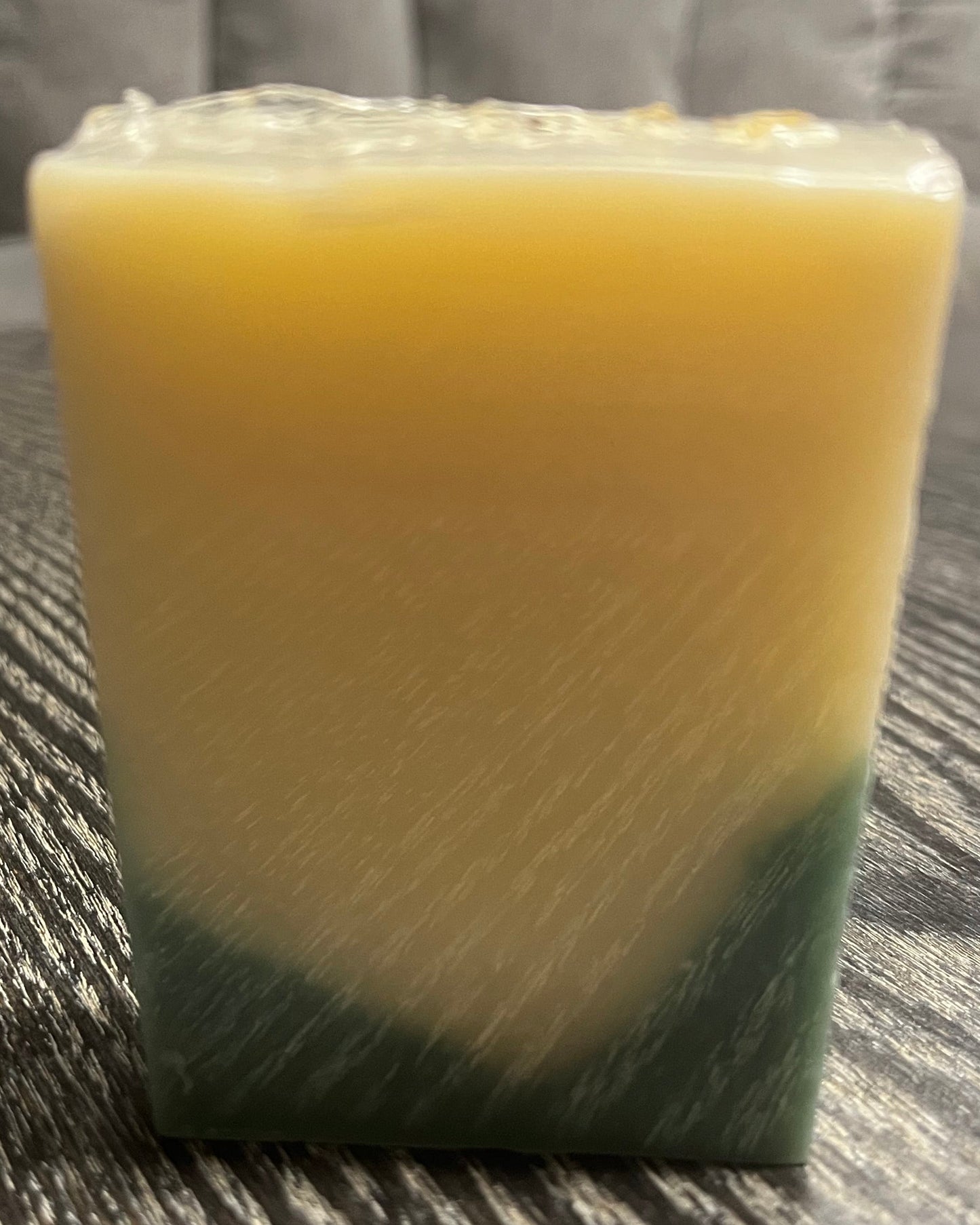A bar of soap showing the back of the bar to show off the green and beige layers. 