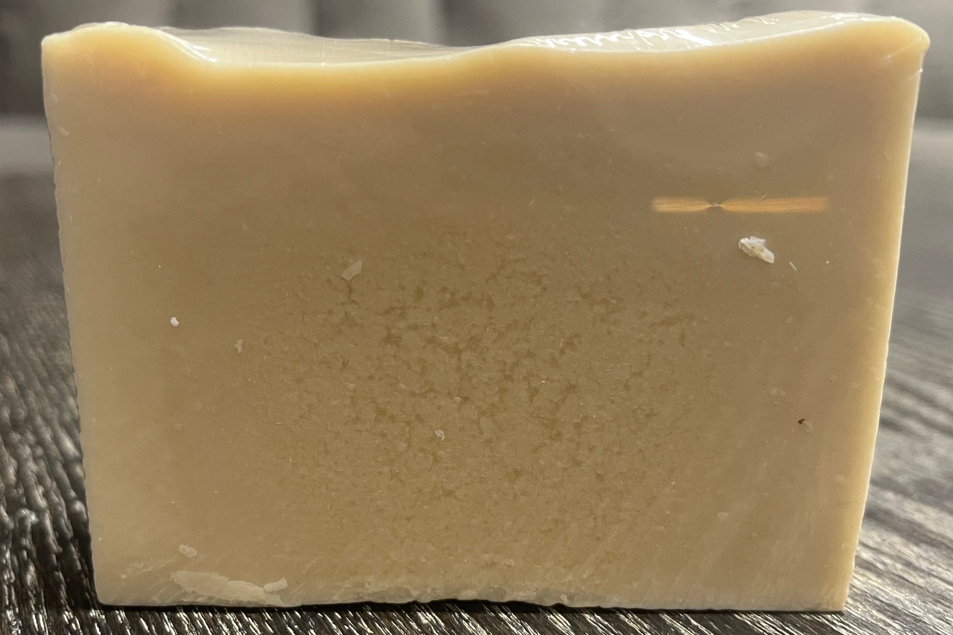 A beige bar of soap on a wooden surface. 