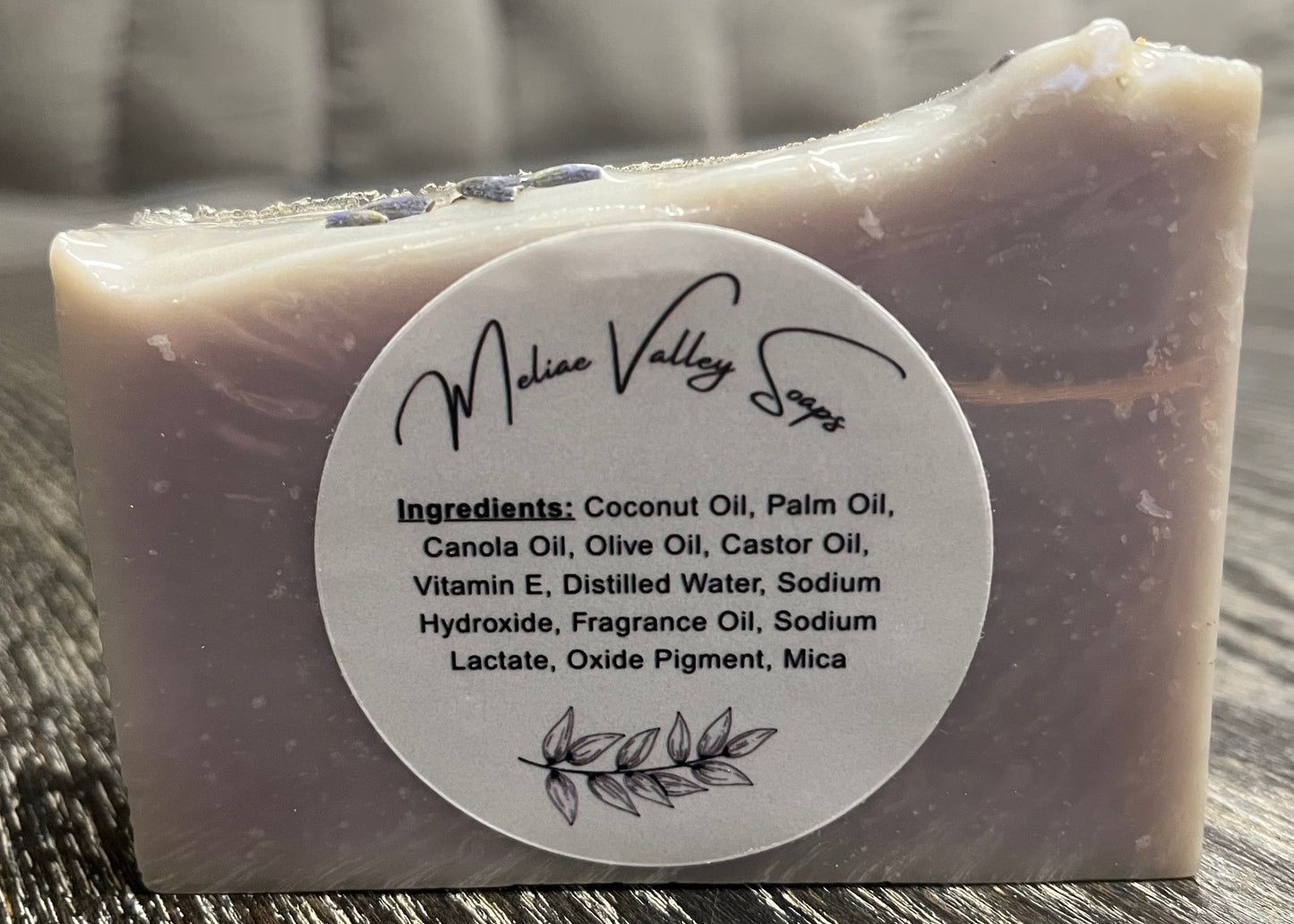 Bar of soap with a white ingredients label on a wooden surface. 