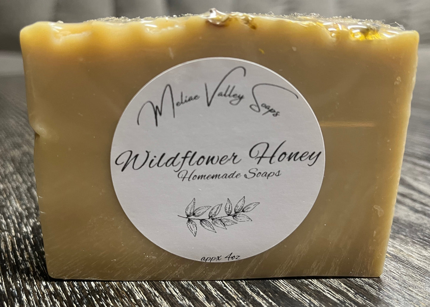 Bar of soap with a label on a wooden surface. 