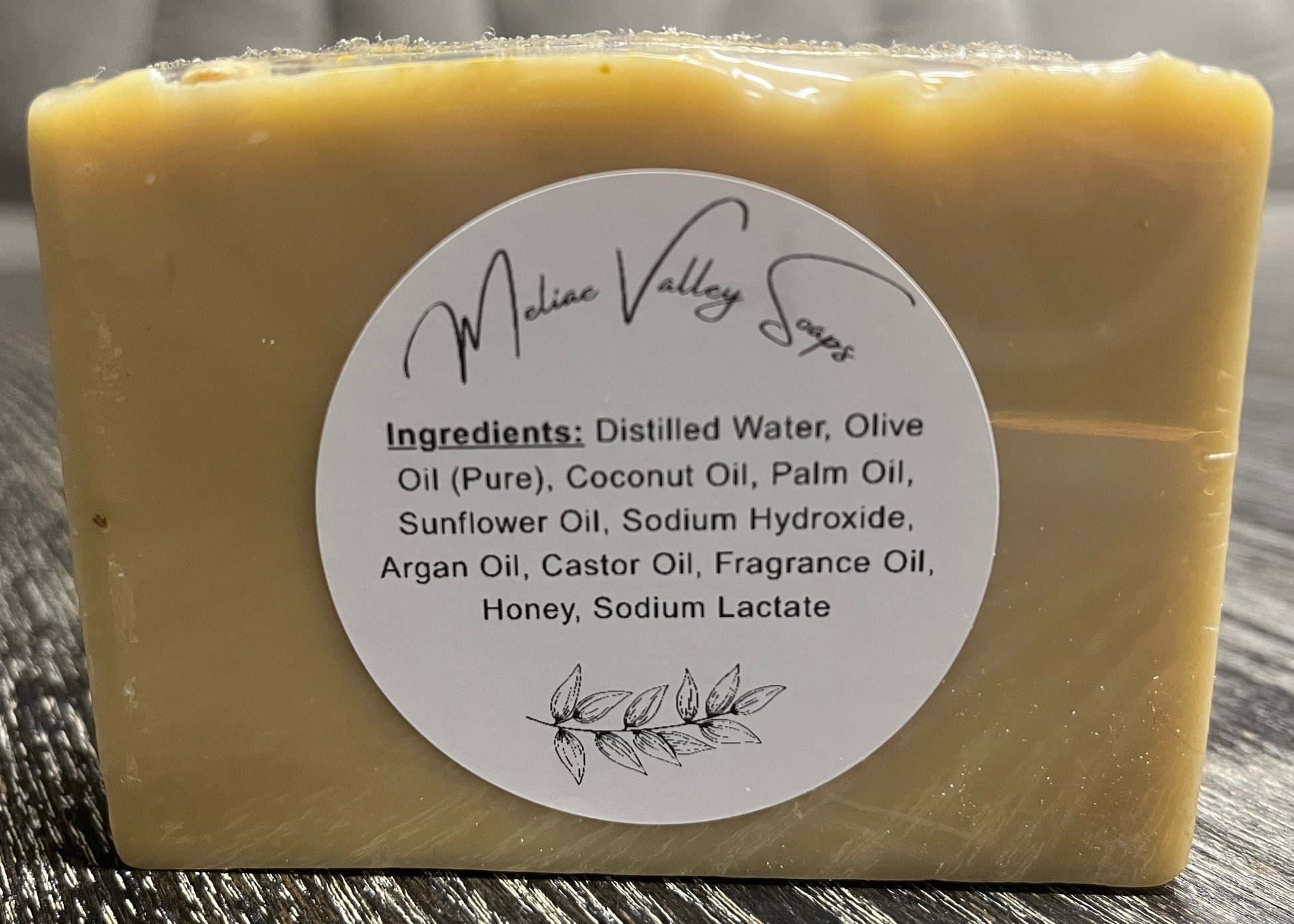 Bar of soap with a white ingredients label on a wooden surface. 