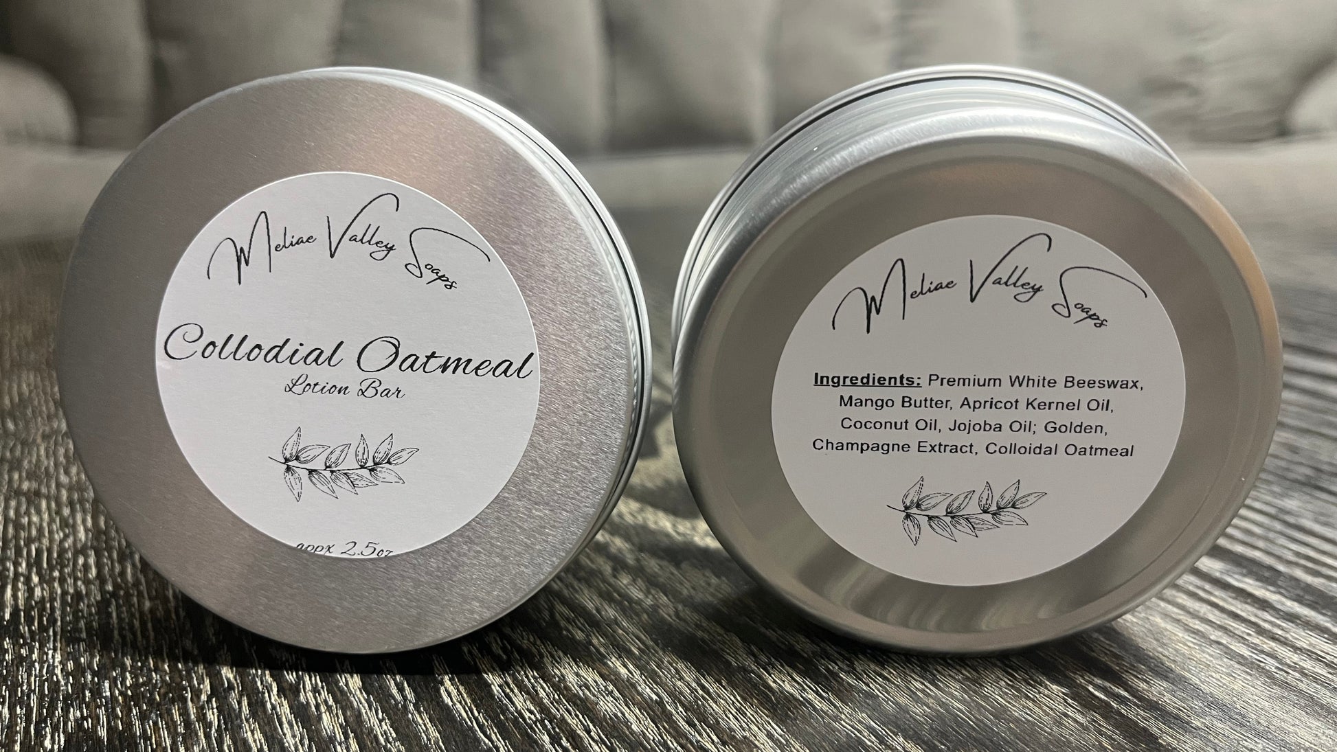 Two tins of lotion bars with white labels on a textured surface with a blurred background. 
