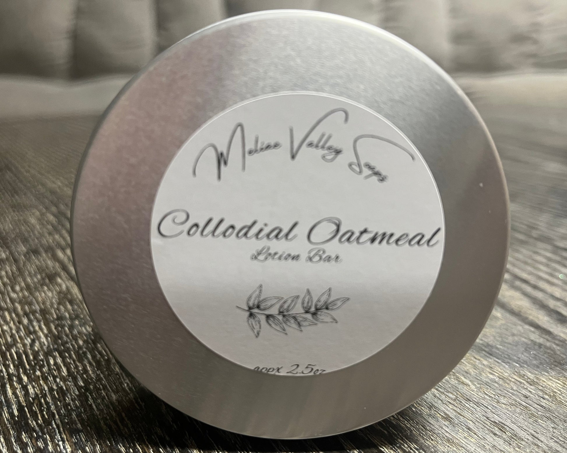 Colloidal Oatmeal lotion bar tin with label on a textured surface