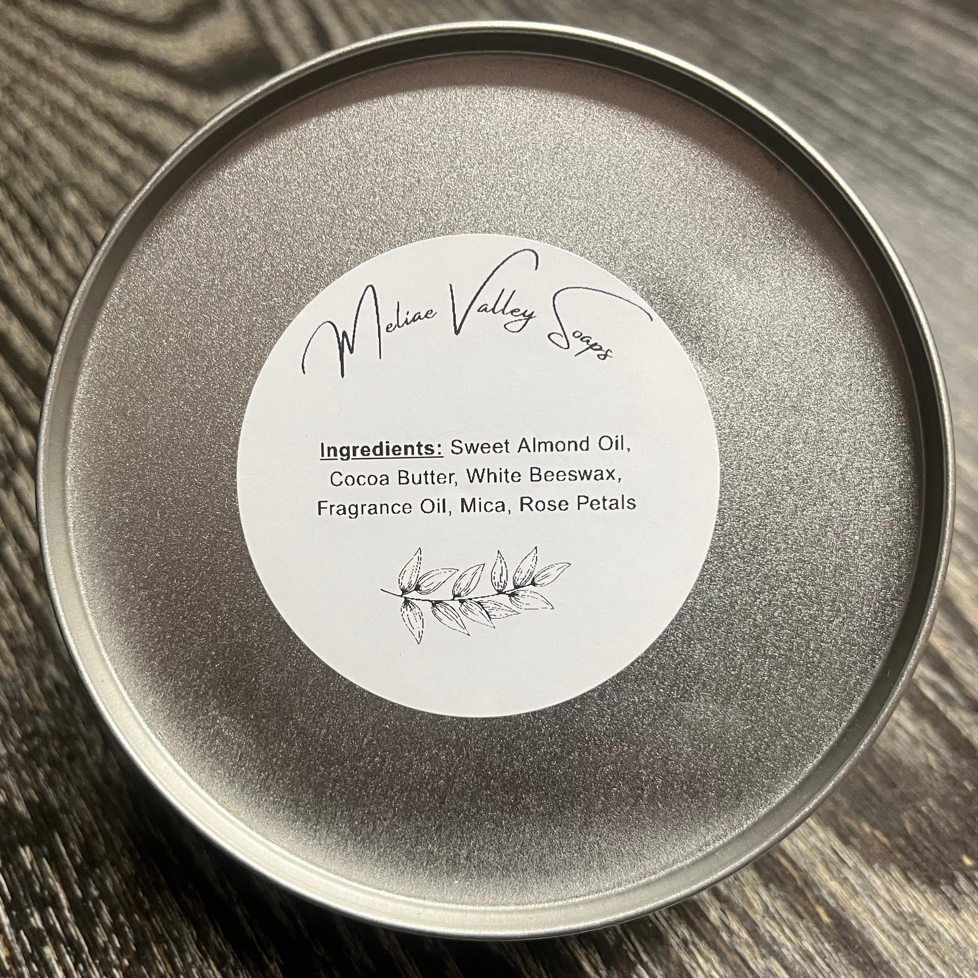 Silver tin with a white ingredients label on a wooden surface. 