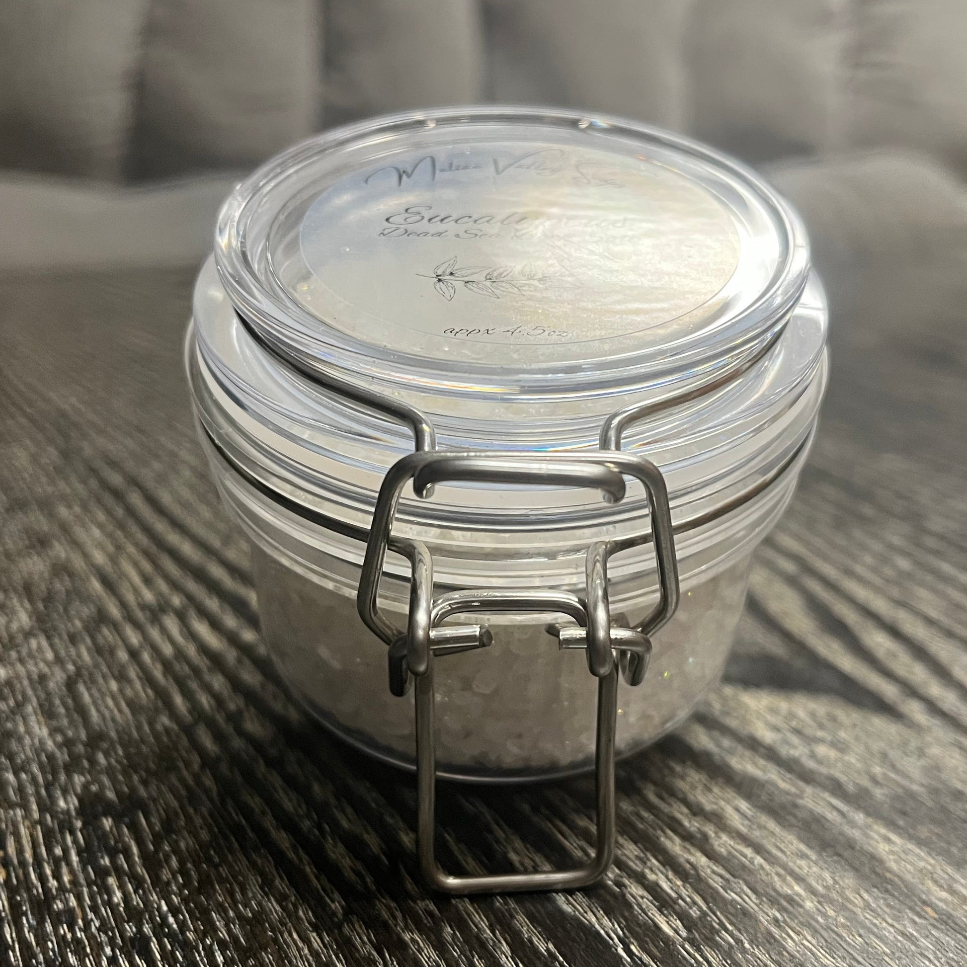 Small jar with a metal clasp on a textured surface. 