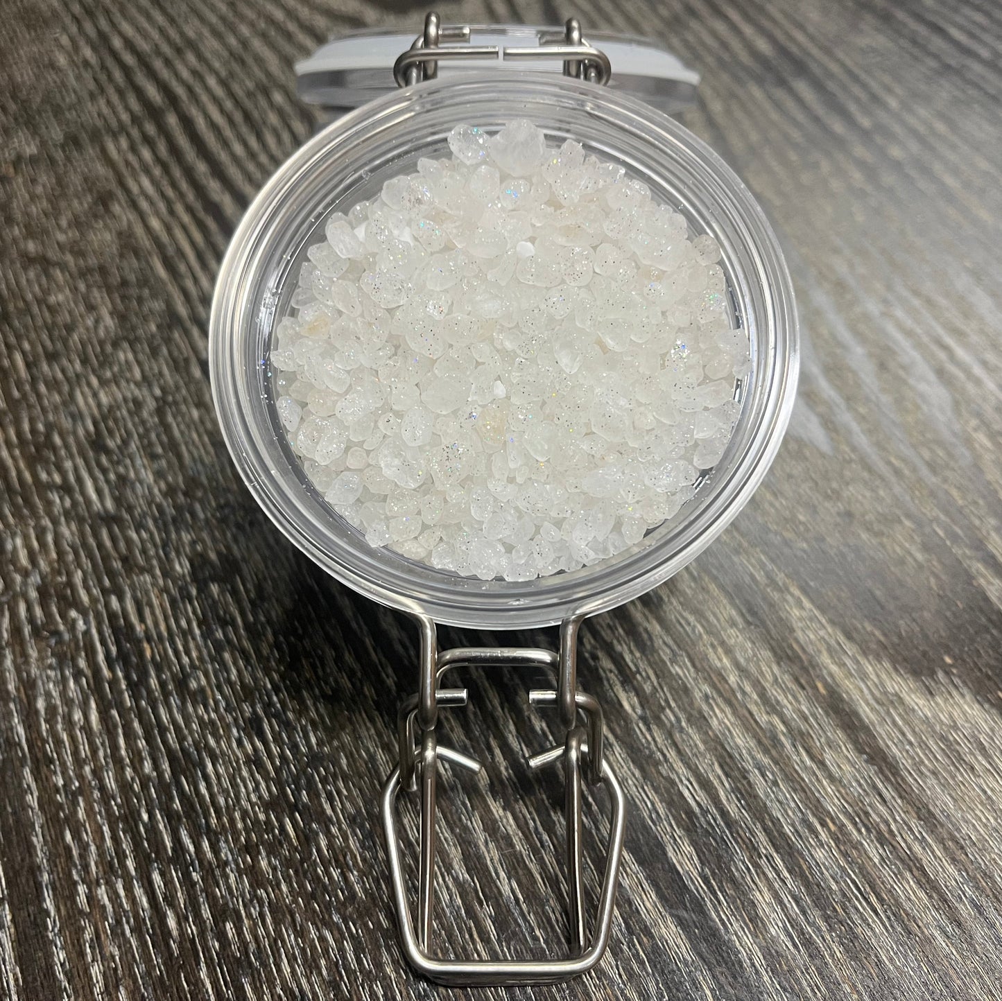 A jar with a lid filled with dead sea salt on a wooden surface. 