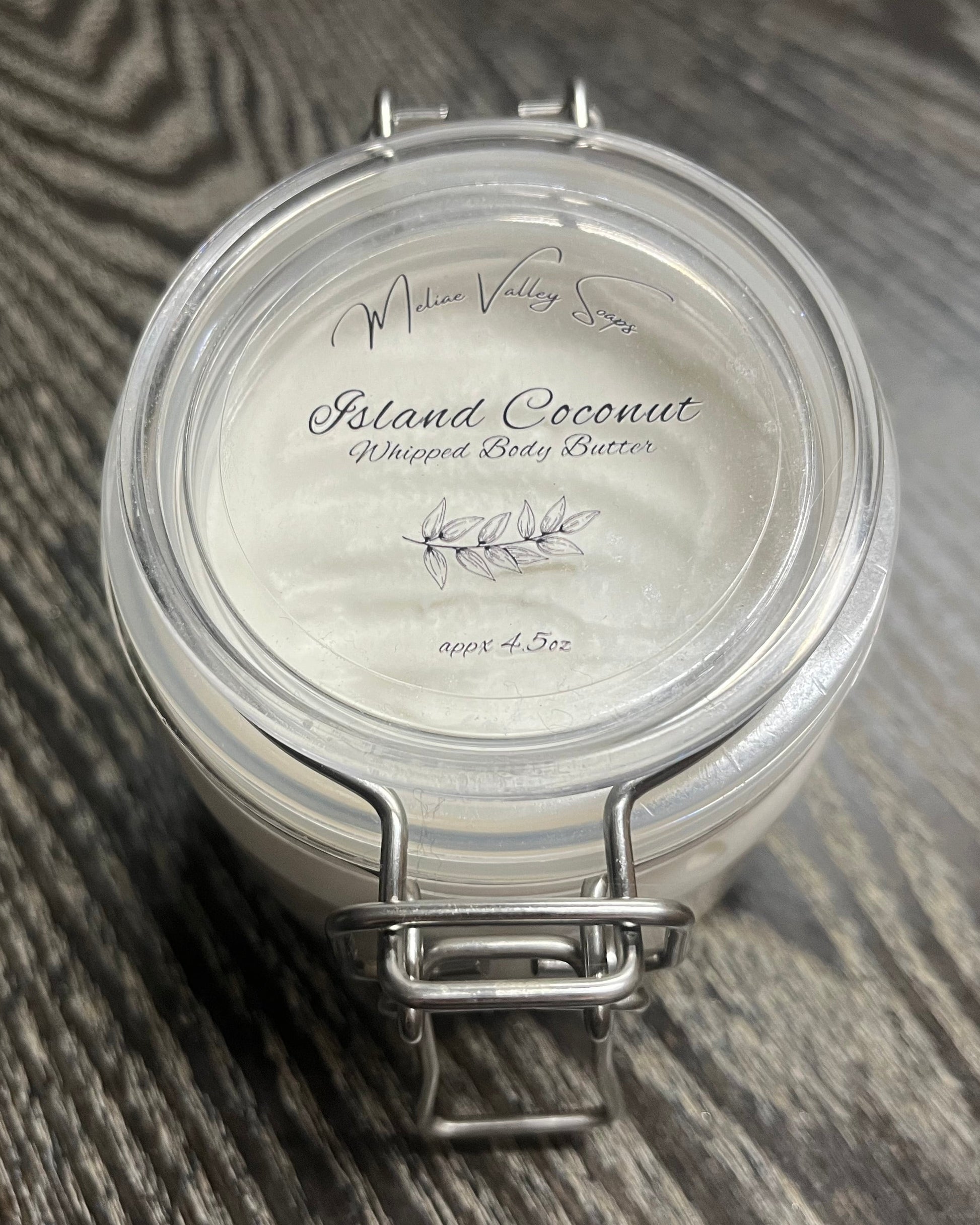 Jar of white whipped body butter with a clear label. 