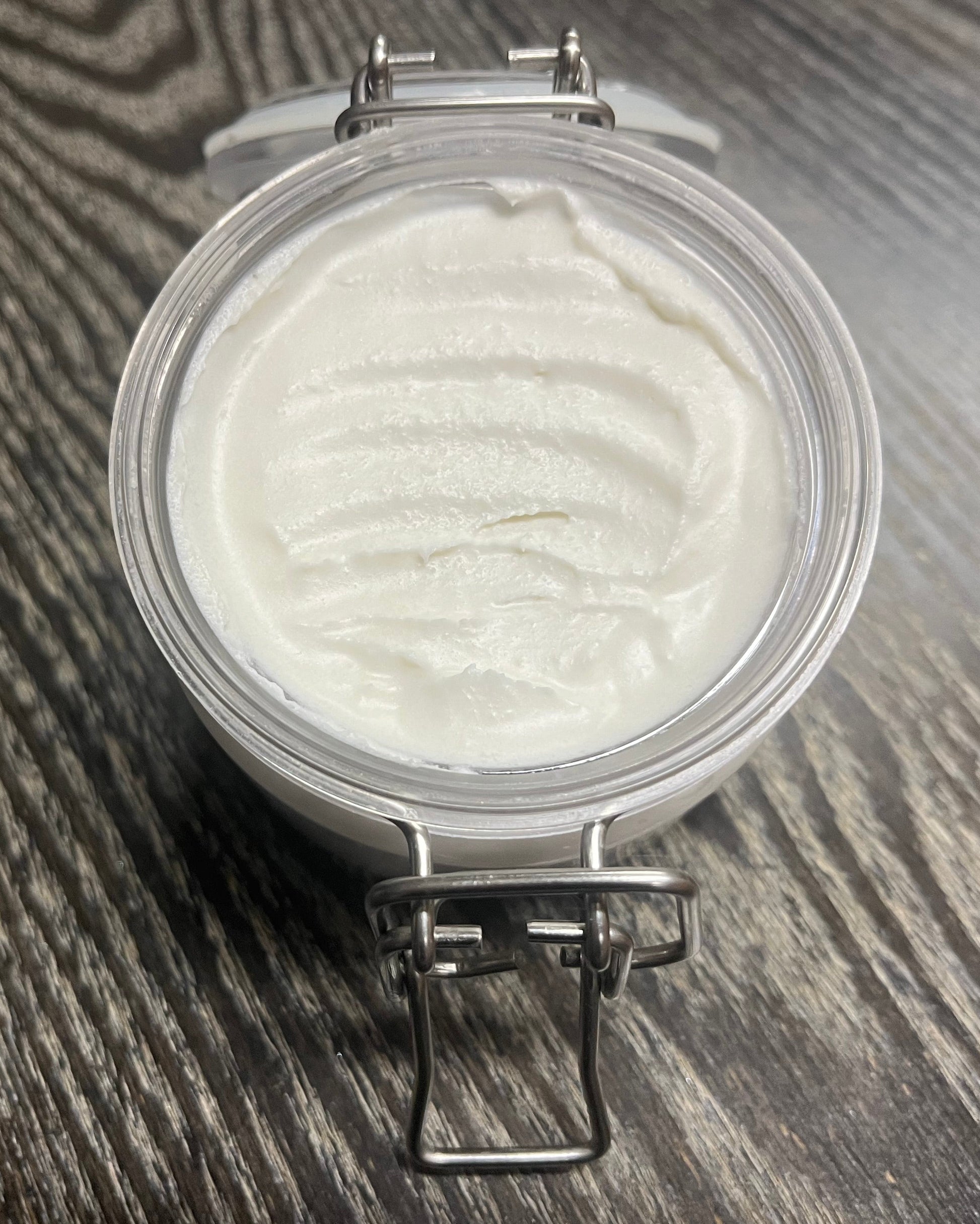 Jar of white whipped body butter on a wooden surface. 