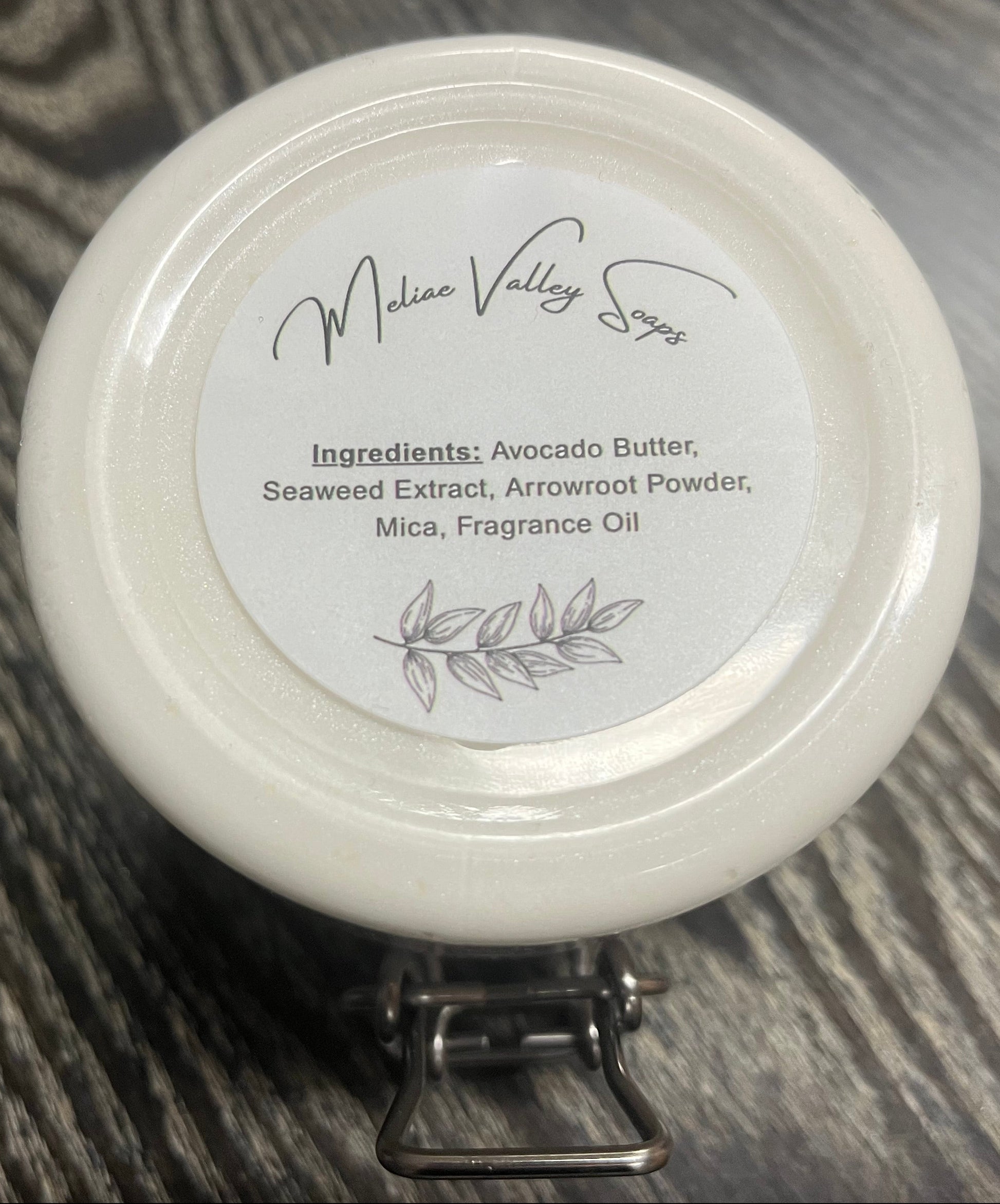 Jar of white whipped body butter with a white ingredients label. 