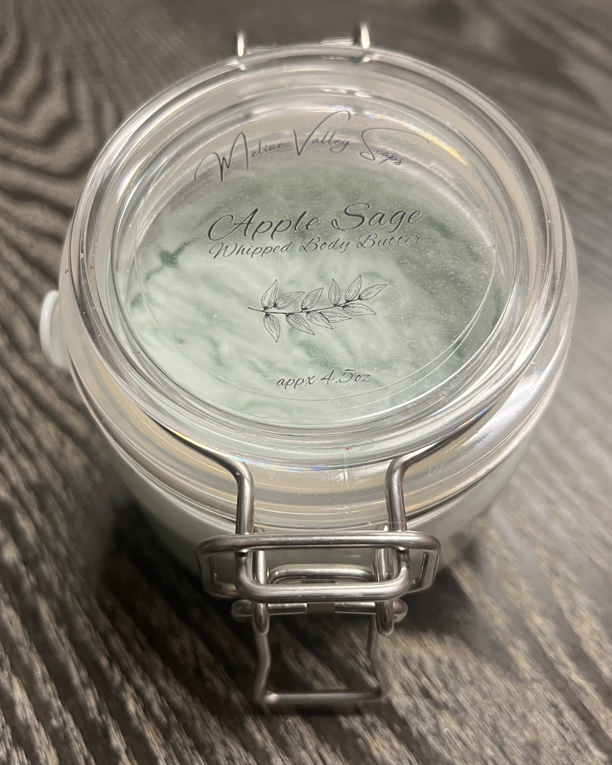 Jar of green whipped body butter with a clear label. 
