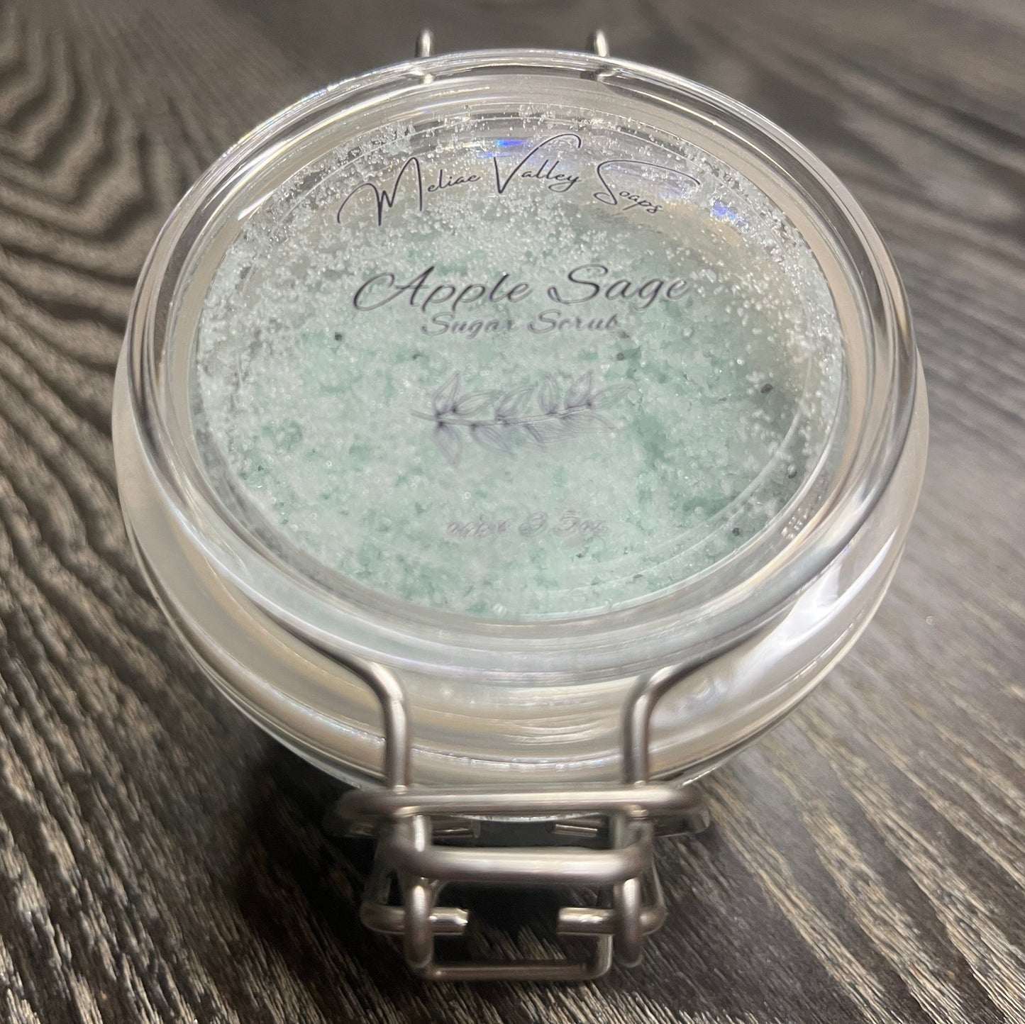 Jar of green body scrub with a clear label. 