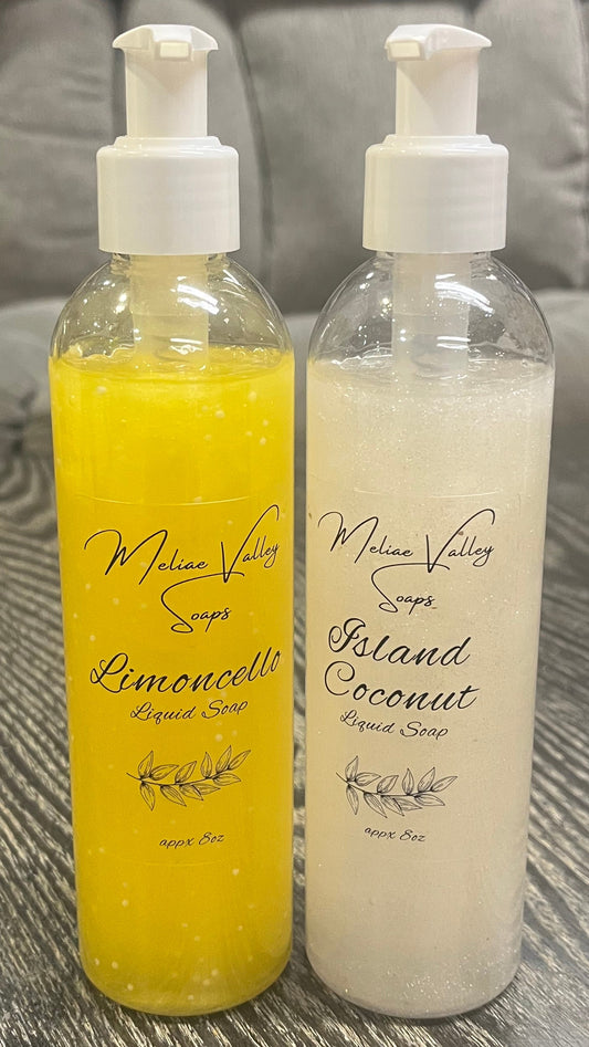 A set of pump bottles with different colored liquids, white and yellow, next to each other on a wooden surface. 