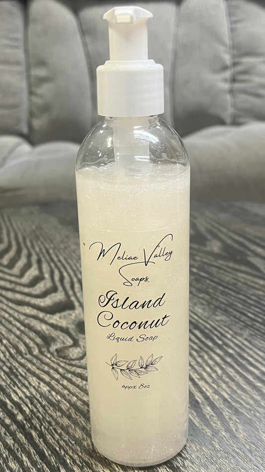 A clear pump bottle with a white nozzle full of red liquid with white beads on a textured surface. 