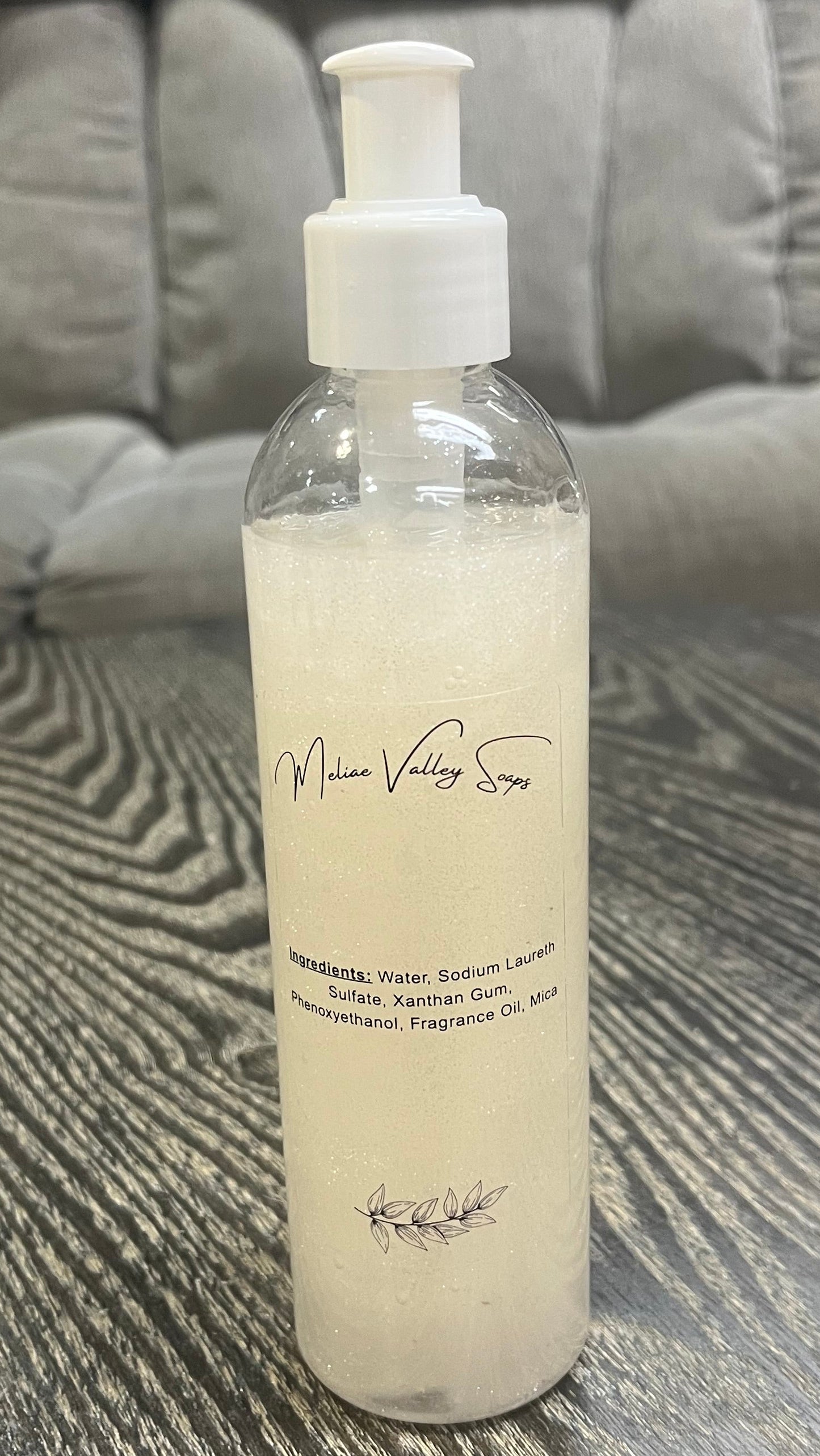 A clear pump bottle with a white nozzle full of red liquid with white beads on a textured surface. 