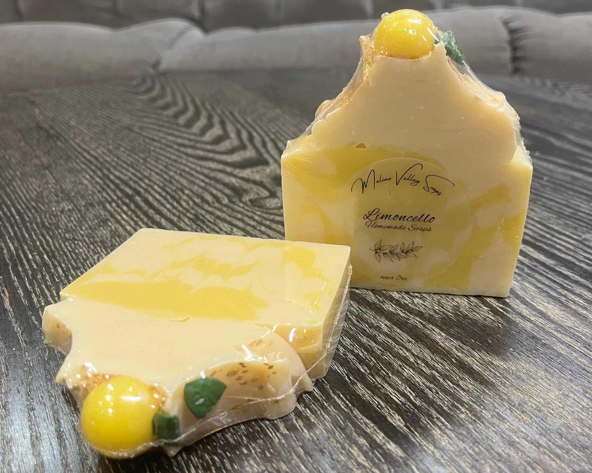 Two pieces of lemon-scented soap on a wooden surface. 