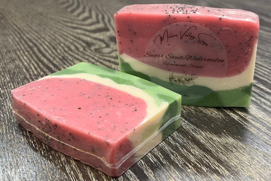 Two bars of pink and green soap on a wooden surface. 