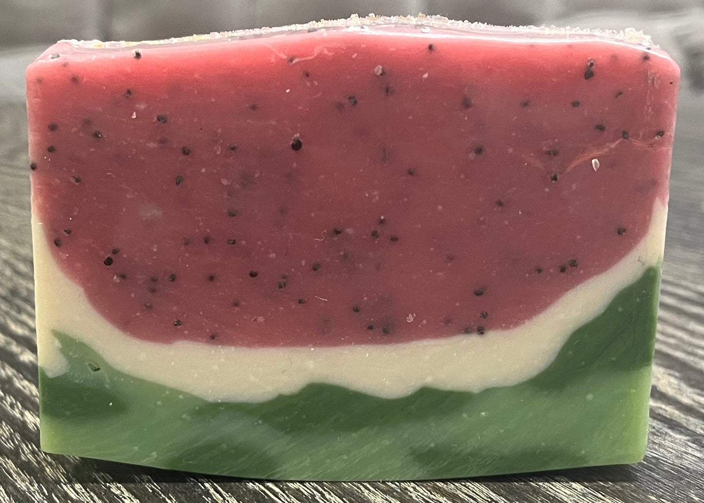 Bar of soap with watermelon pattern on a textured surface. 