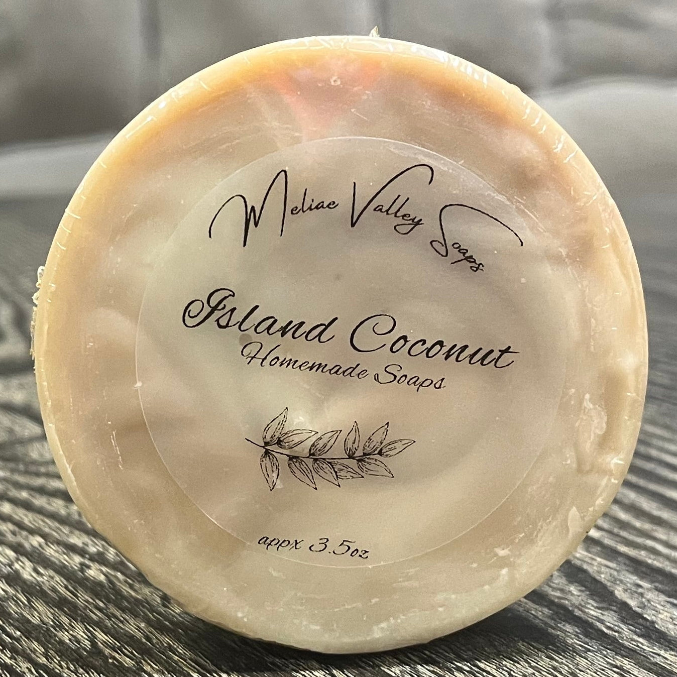 Round soap bar with 'Island Coconut' branding on a textured surface.