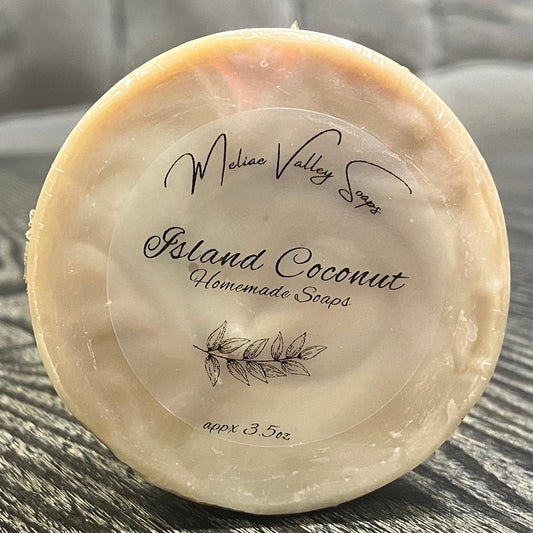 Round soap bar with 'Island Coconut' branding on a textured surface.