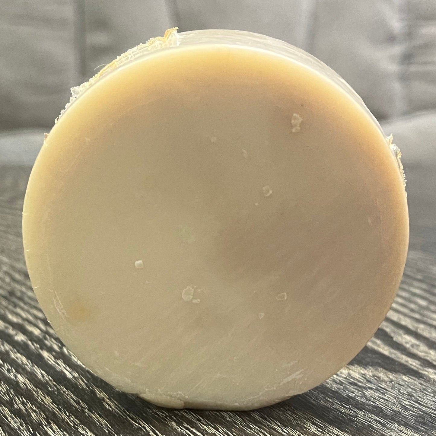Round beige soap on a textured surface with a blurred background. 