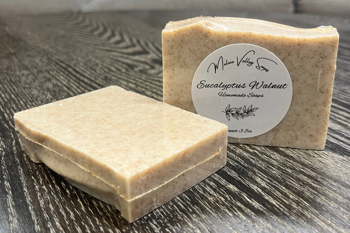 Two soap bars on a wooden surface with a label on one of them.