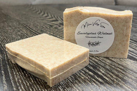 Two soap bars on a wooden surface with a label on one of them.