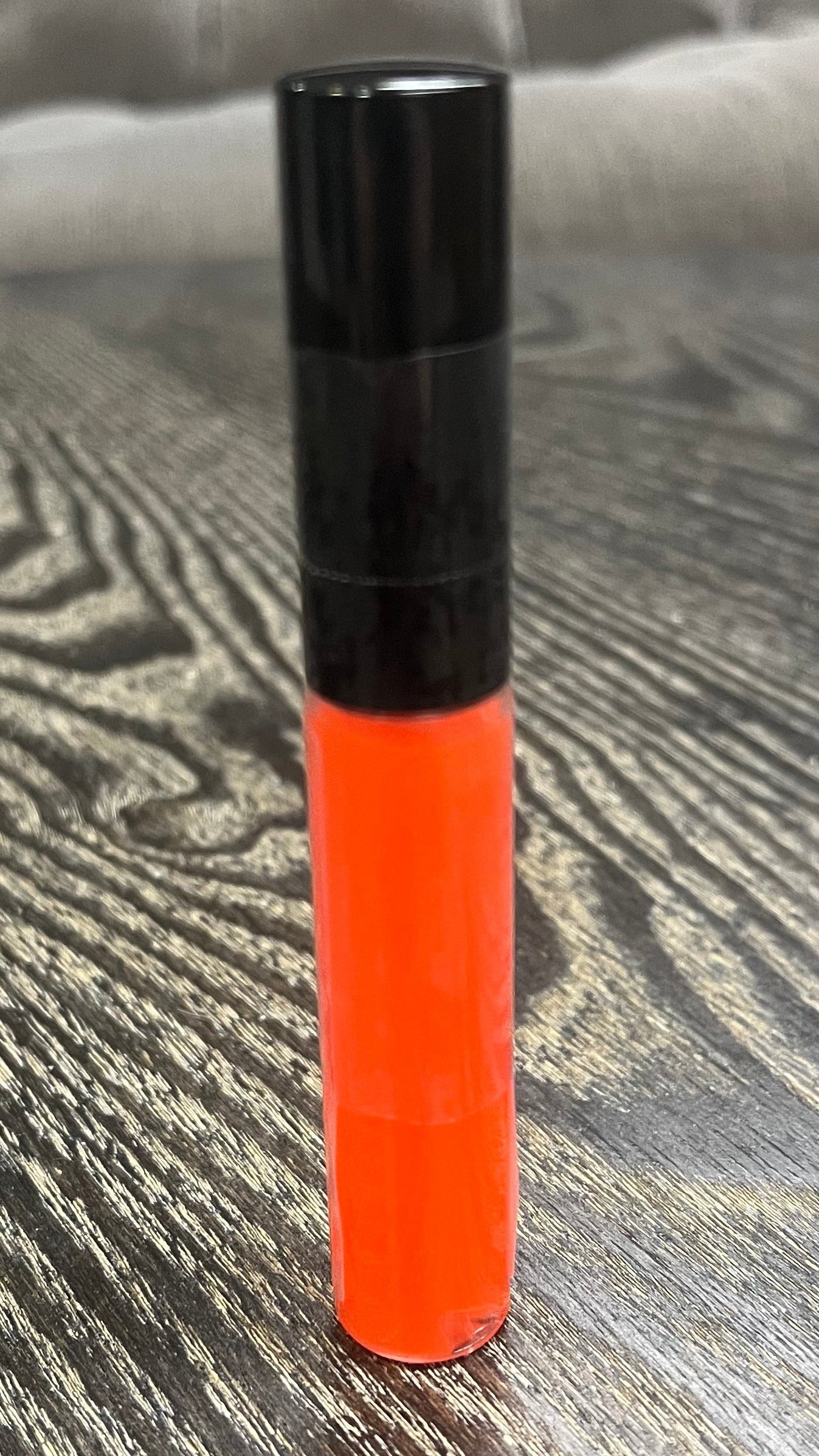 A bright orange tube of lip gloss. 